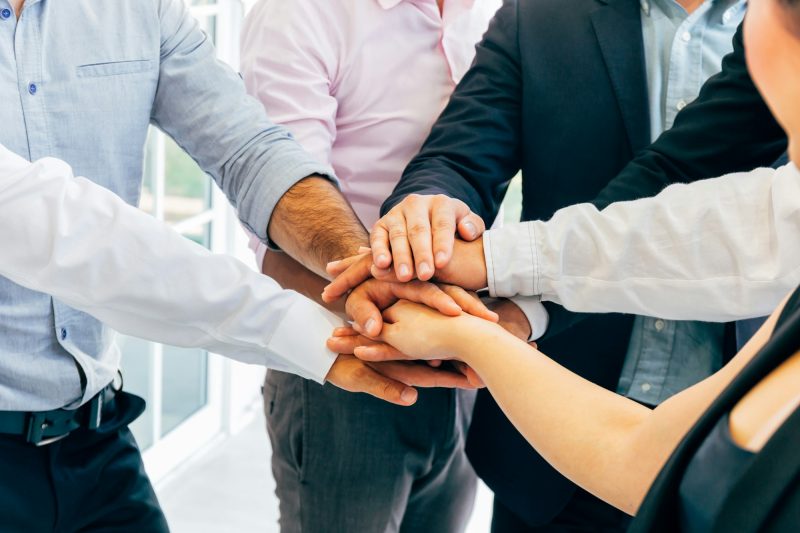 Business people putting hands togehter for unity